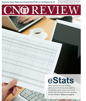 Image of a hand holding a spreadsheet with a computer tablet in the background Image of a hand holding a spreadsheet with a computer tablet in the background