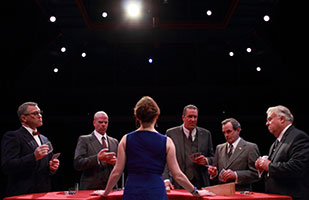 Image of five men in suits standing around a poker table with a female dealer (Ben Sostrom)