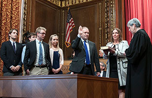 Image of Justice Pat DeWine taking the oath of office from Ohio Supreme Court Chief Justice Maureen O'Connor as DeWine's wife and children watch