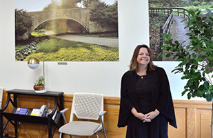 Image of a woman standing in front of large portraits depicting nature scenes