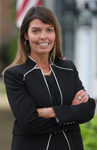 Image of a woman in a black suit standing with her arms crossed