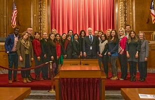 Image of a group of men and women standing gathered in the courtroom of the Thomas J. Moyer Ohio Judicial Center