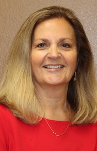 Image of a smiling woman with long, blond hair, wearing a red blouse