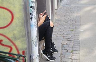 Image of a juvenile sitting on a step in a graffiti-covered doorway