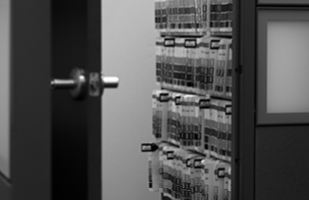 Image of an open door showing the inside of a room full of file folders on shelves