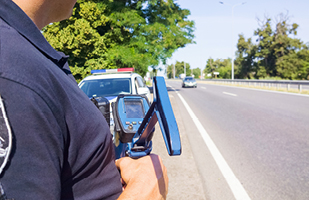 Image of a police officer holding a laser speed-measuring device (istock/Evgen_Prozhyrko)