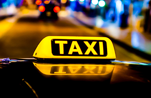 Image of an illuminated taxi sign on the roof of a taxi.