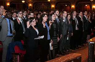 Image of new lawyers, right hands raised in the air, taking the oath of office