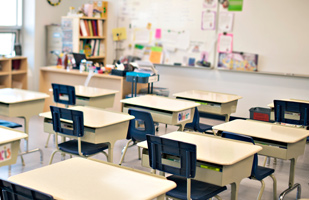 Image of rows of empty school desks in a classroom.