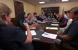 Image of people sitting around a table in a jury deliberation room. Image of people sitting around a table in a jury deliberation room.