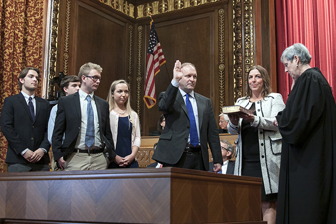 Image of Justice Pat DeWine taking the oath of office from Ohio Supreme Court Chief Justice Maureen O'Connor as DeWine's wife and children watch