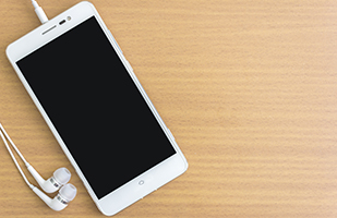 Image of a smartphone with ear buds lying on a table (THINKSTOCK)