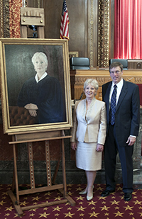 Image of former Ohio Supreme Court Justice Judith Ann Lanzinger and portrait artist Jeffrey Klopping standing by a portrait of former Justice Lanzinger