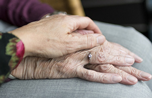 Image of an elderly person's hands being held by another person's hand