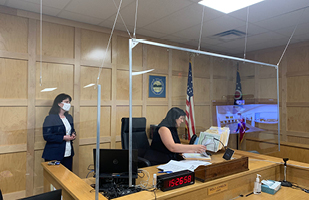 Image of two women in a courtroom equipped with plexiglass barriers