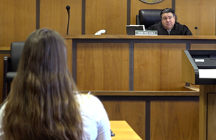 Image of a male judge sitting on the bench looking at a woman defendant