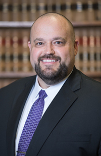 Image of a smiling man with a beard wearing a suit