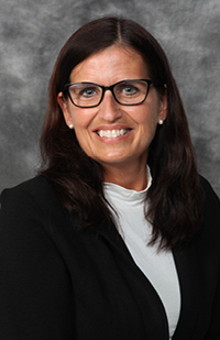 Image of a woman with long, dark hair, wearing classes and a black blazer