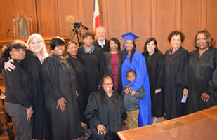 Image of several men and women, many wearing black judicial robes, standing side-by-side in a courtroom