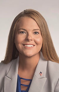 Caucasian woman with blonde hair wearing a suit jacket smiling.