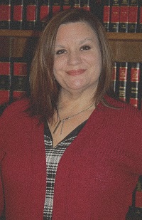 Image of Caucasian with brunette hair standing in front of a bookcase.