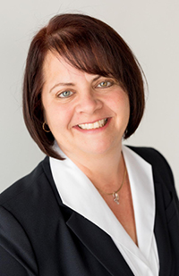 Image is a headshot photo of Judge-designate Elizabeth Schuller wearing a white blouse and black blazer