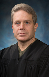 Image of a male judge wearing a black judicial robe.