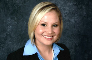 Image of a woman with blonde hair wearing a blue blouse and black blazer.