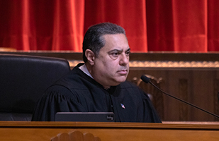 Image of a male judge with short, dark hair wearing a black judicial robe.