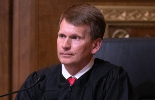 Image of a male judge wearing a black judicial robe.