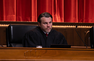 Image of a male judge wearing a black judicial robe seated at the bench in the courtroom of the Thomas J. Moyer Ohio Judicial Center.