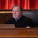 Image of a male judge wearing a black judicial robe seated at the bench in the courtroom of the Thomas J. Moyer Ohio Judicial Center.