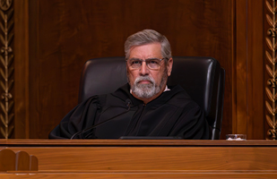 Image of a male judge wearing a black judicial robe seated at the bench in the courtroom of the Thomas J. Moyer Ohio Judicial Center.