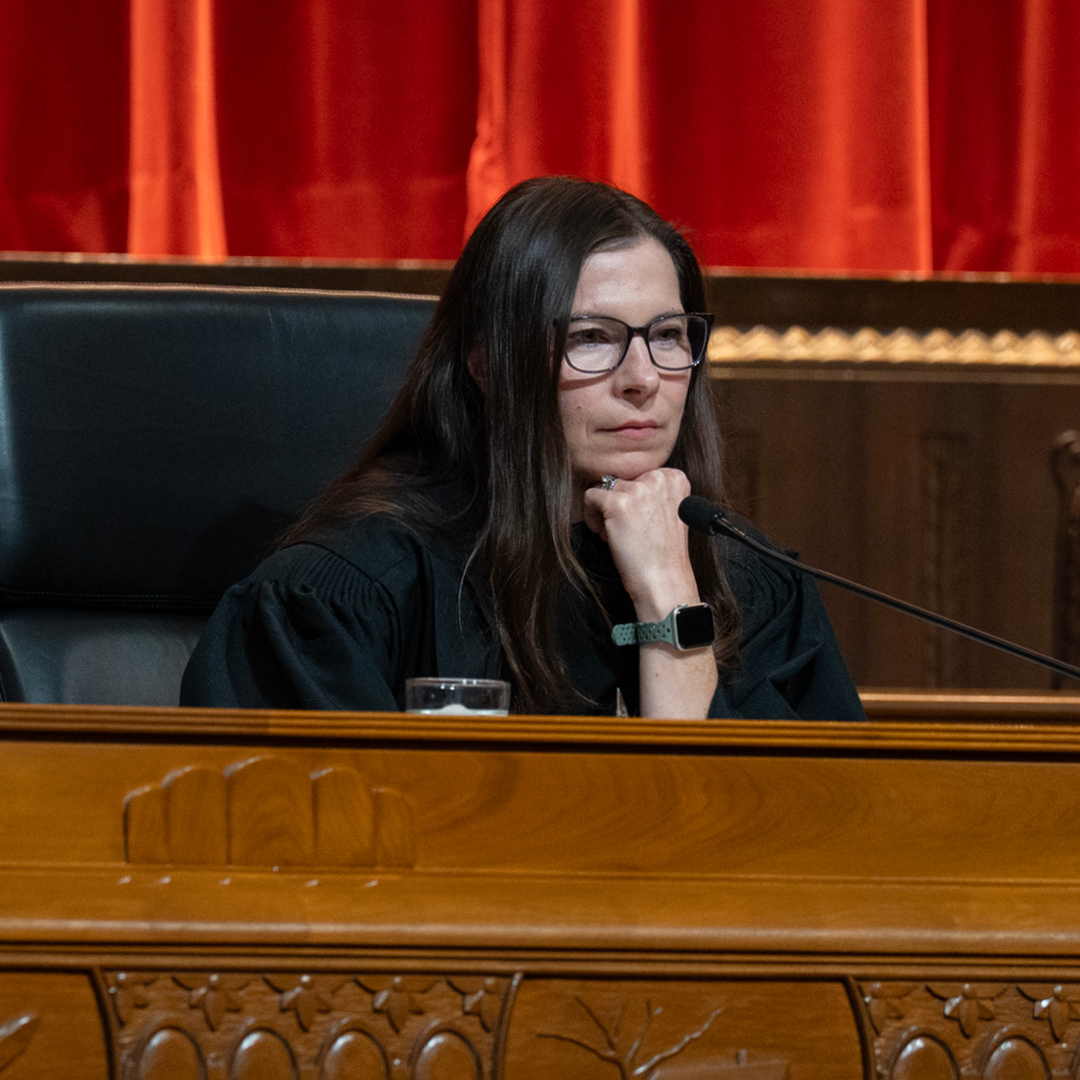 A woman judge with her hand on her chin sitting on the bench in the Thomas J. Moyer Ohio Judicial Center Courtroom