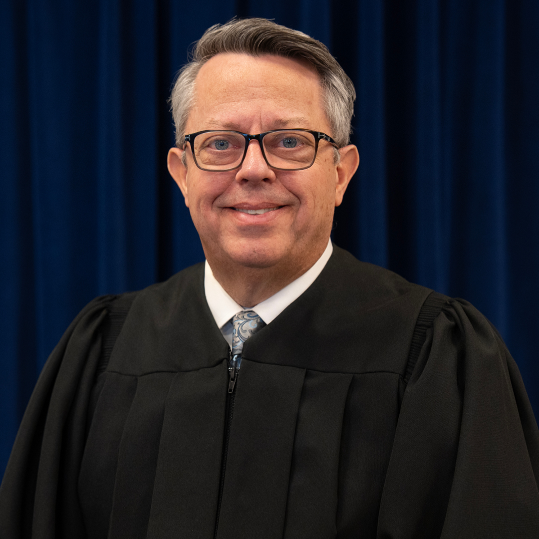 Male judge wearing a black judicial robe.