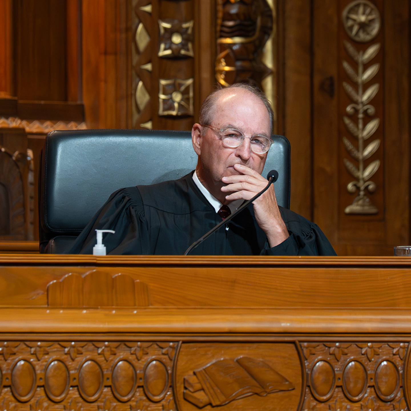 A judge in a black robe sitting at a wooden bench
