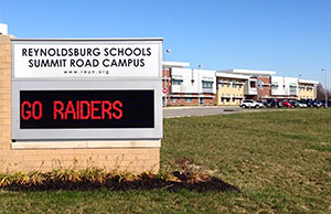 Image of the Reynoldsburg Schools Summit Road Campus sign with the school in the background
