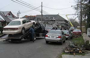 Image of a tow truck loading a white car onto the tow truck while in a residential neighborhood