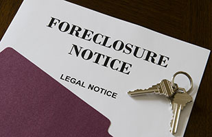 Image of a legal notice of foreclosure sticking out of a file folder with a set of house keys lying on top (Thinkstock)