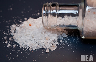 Image of a clear bottle lying on its side with bath salts spilling out (U.S. Drug Enforcement Administration)