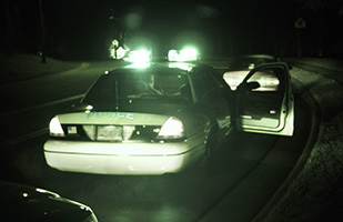 Image of a police cruiser with its passenger door open making a traffic stop (THINKSTOCK)