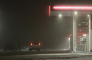 Image of a gas station at night time, with two cars in its parking lot
