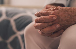 Image of what appear to be an elderly person's clasped hands on the person's lap (iStock/Goodboy Picture Company)