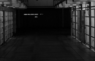Image of a darkened prison hallway lined with jail cells