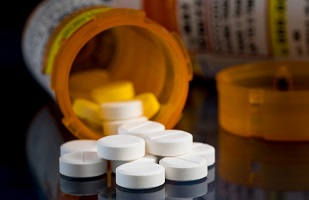 Prescription pill bottles opened with pill spilling out onto a table.