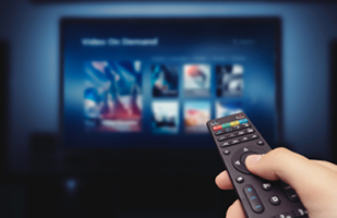 Image of a bunch of different colored vertical lines next to a hand holding a television remote pointed at a flat screen tv
