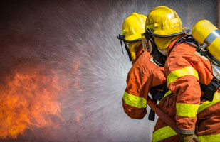 Image of two firefighters putting out a raging fire