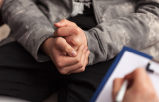 Image showing a young person's hands and arms appearing as if they are handcuffed.