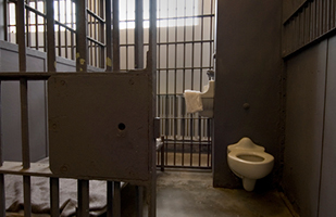 Image of an empty prison cell with the cell door open.