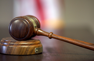 Closeup image of a wooden gavel resting on a wooden sound block.